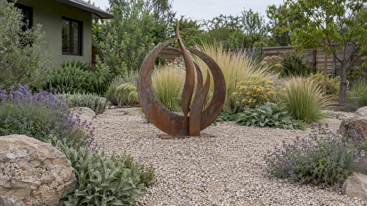 Weathered metal sculpture in a gravel garden